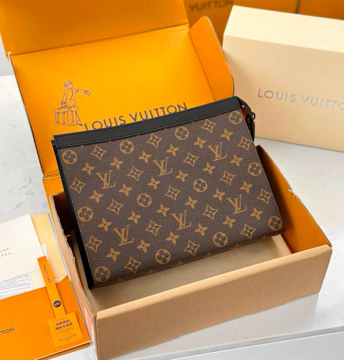 Louis Vuitton monogram canvas pouch in an open Louis Vuitton box, with branded packaging visible around it on a light surface.